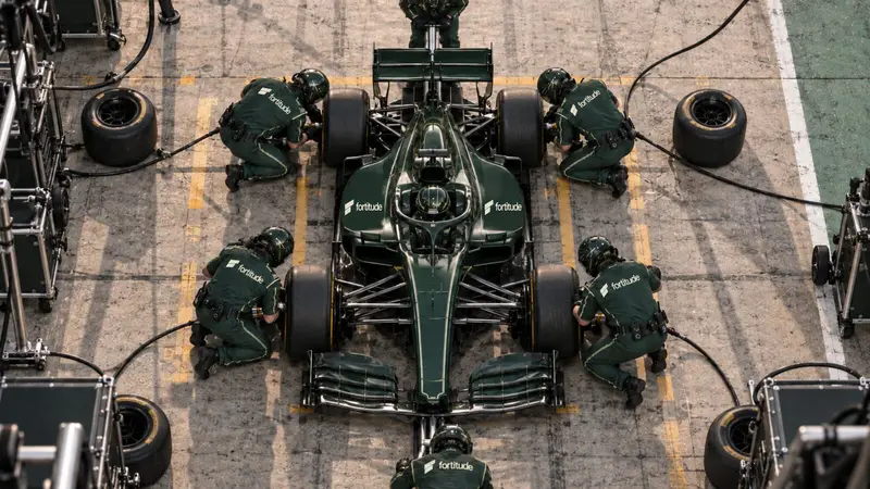 A pit crew working on a green racing car, seen from directly overhead